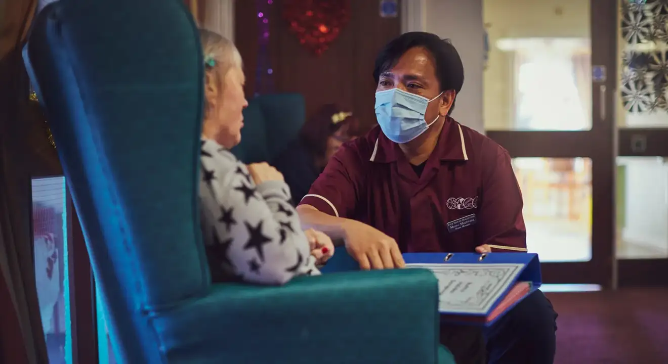 Nurse speaking to elderly lady in her chair