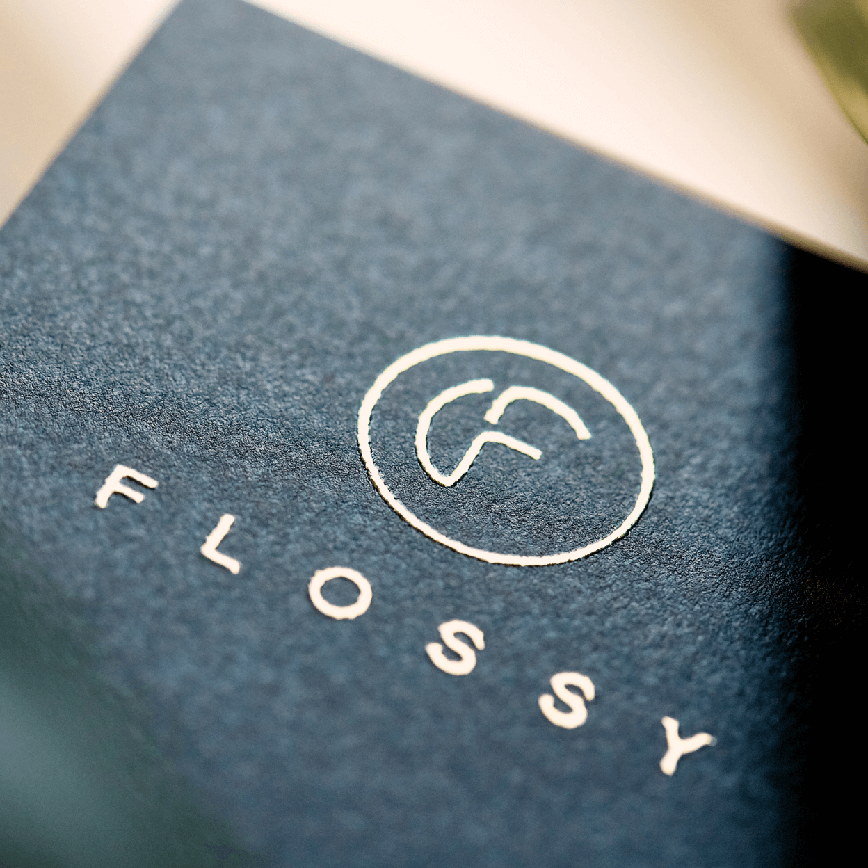 Het logo van Flossy in het goud gedrukt op papier.