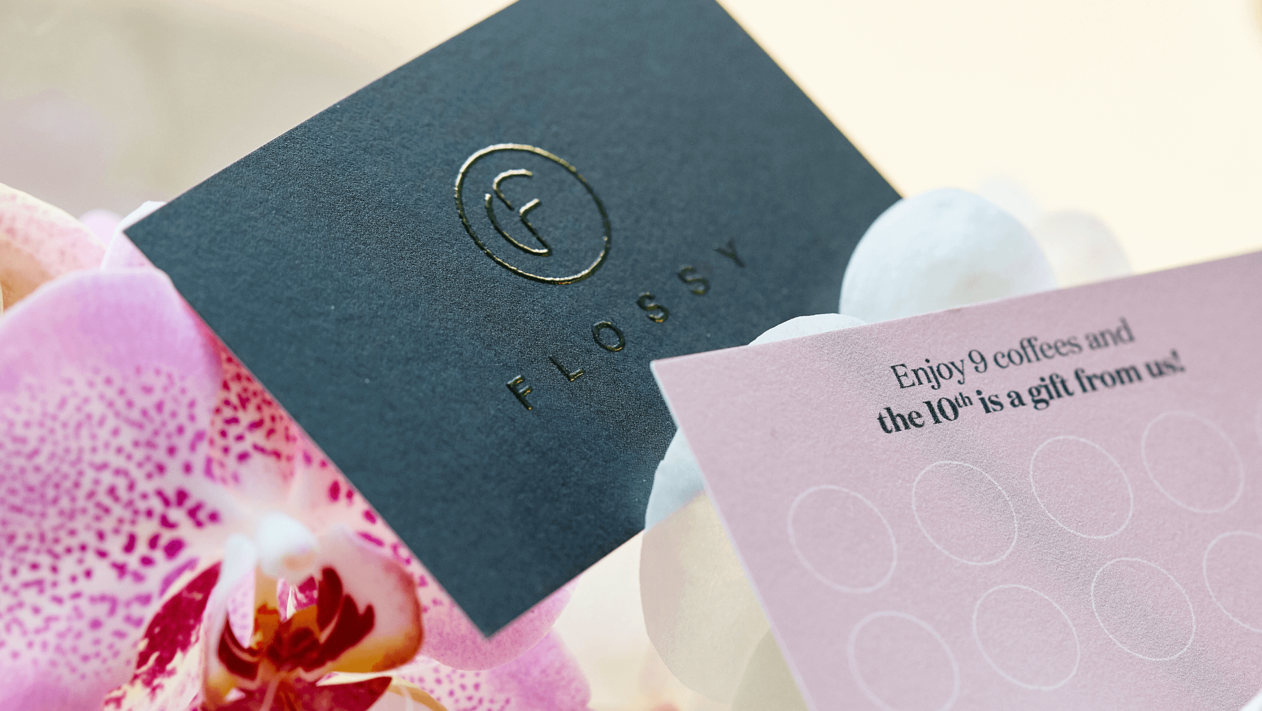 Een koffie stempelkaartje met het goud bedrukte logo van Flossy.