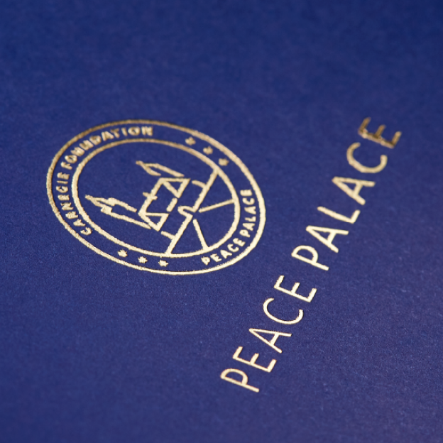 Het logo van het Vredespaleis in goud gedrukt op papier.