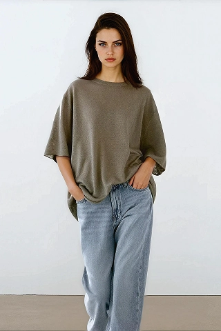 Aurora, a Botika AI fashion model wearing an oversized green tshirt and jeans. 