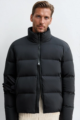 Botika male AI fashion model Sebastian wearing a black puffer jacket zipped up. 