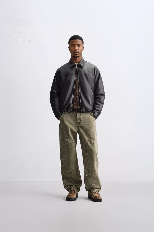 A Botika black male AI fashion model, Eric in a brown leather jacket, and light army green linen pants.