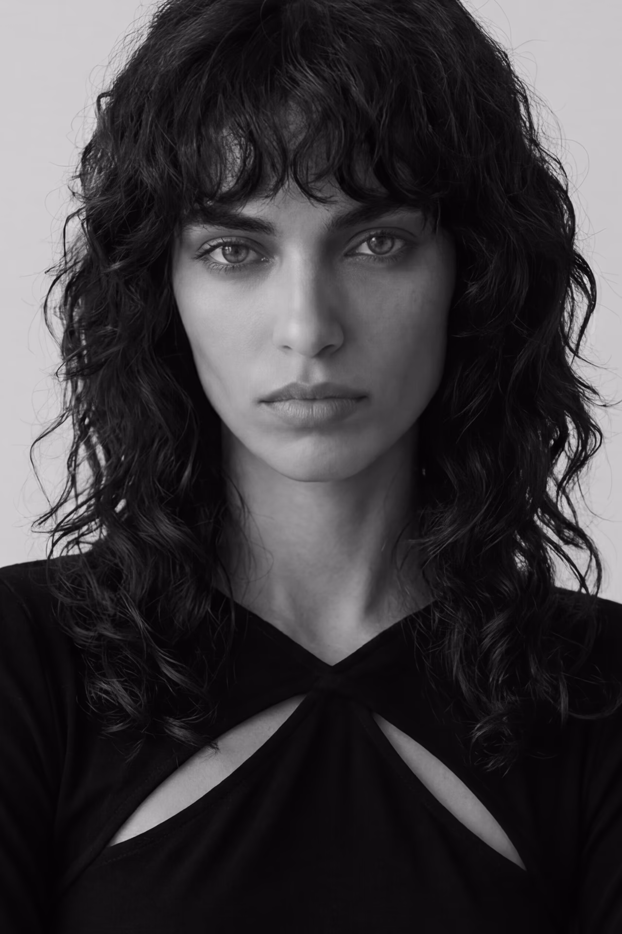 Black and white headshot of Rita, a Botika AI fashion model wearing a black top with cut outs just below each shoulder.