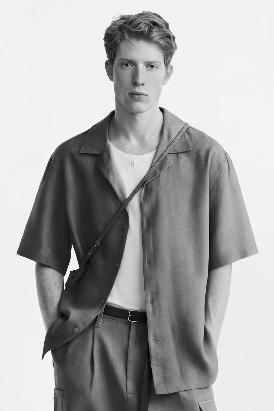 Botika's red haired male AI fashion model Theo in his headshot wearing an oatmeal collared v-neck sweater with a white tshirt underneath.