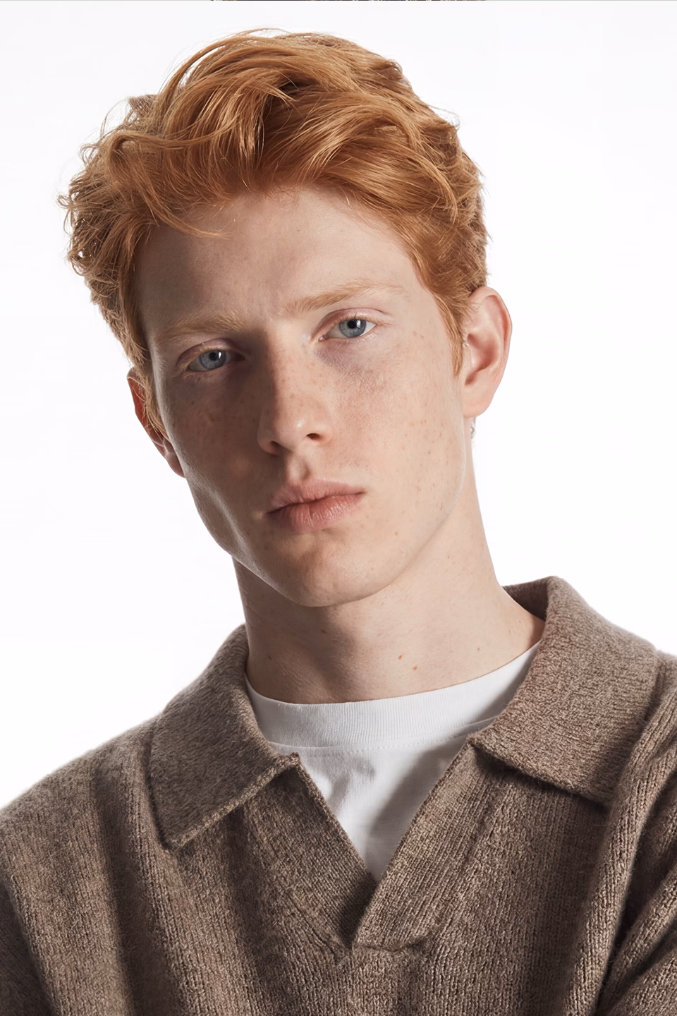 Botika's red haired male AI fashion model Theo in his headshot wearing an oatmeal collared v-neck sweater with a white tshirt underneath.