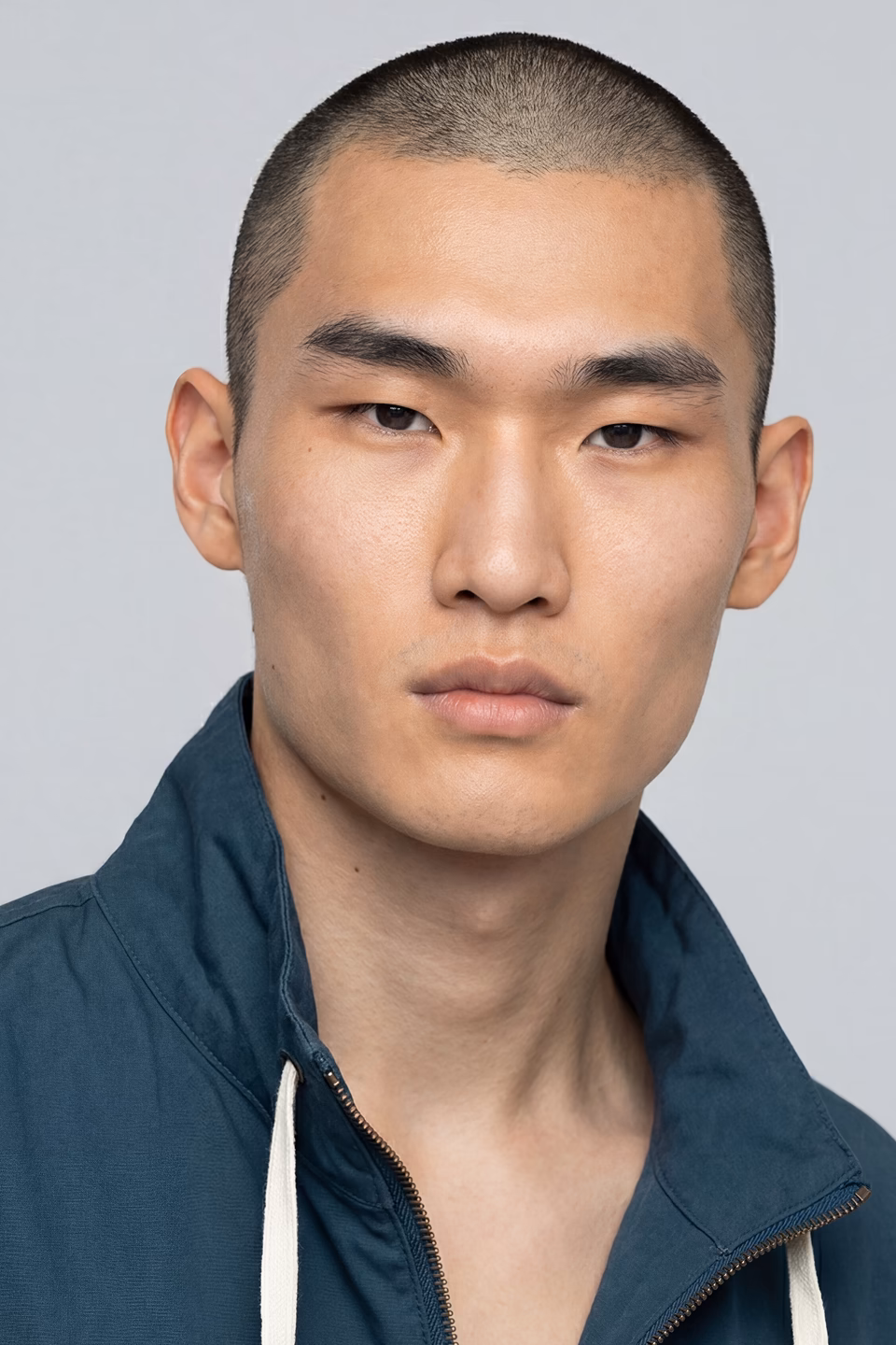 Botika male Asian male AI fashion model Kazuto's headshot wearing a blue zip up sweatshirt.