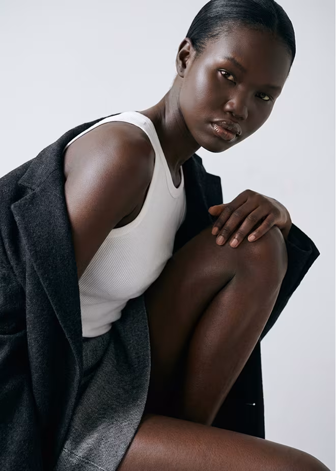 Botika's AI fashion model Ayo. She is a black female wearing a one shoulder gold top and matching bracelet and earrings.