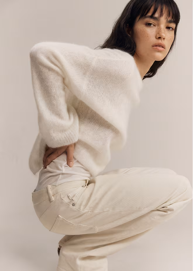 Botika's female dark haired AI fashion model Leona, is modeling a black backless outfit in side profile.