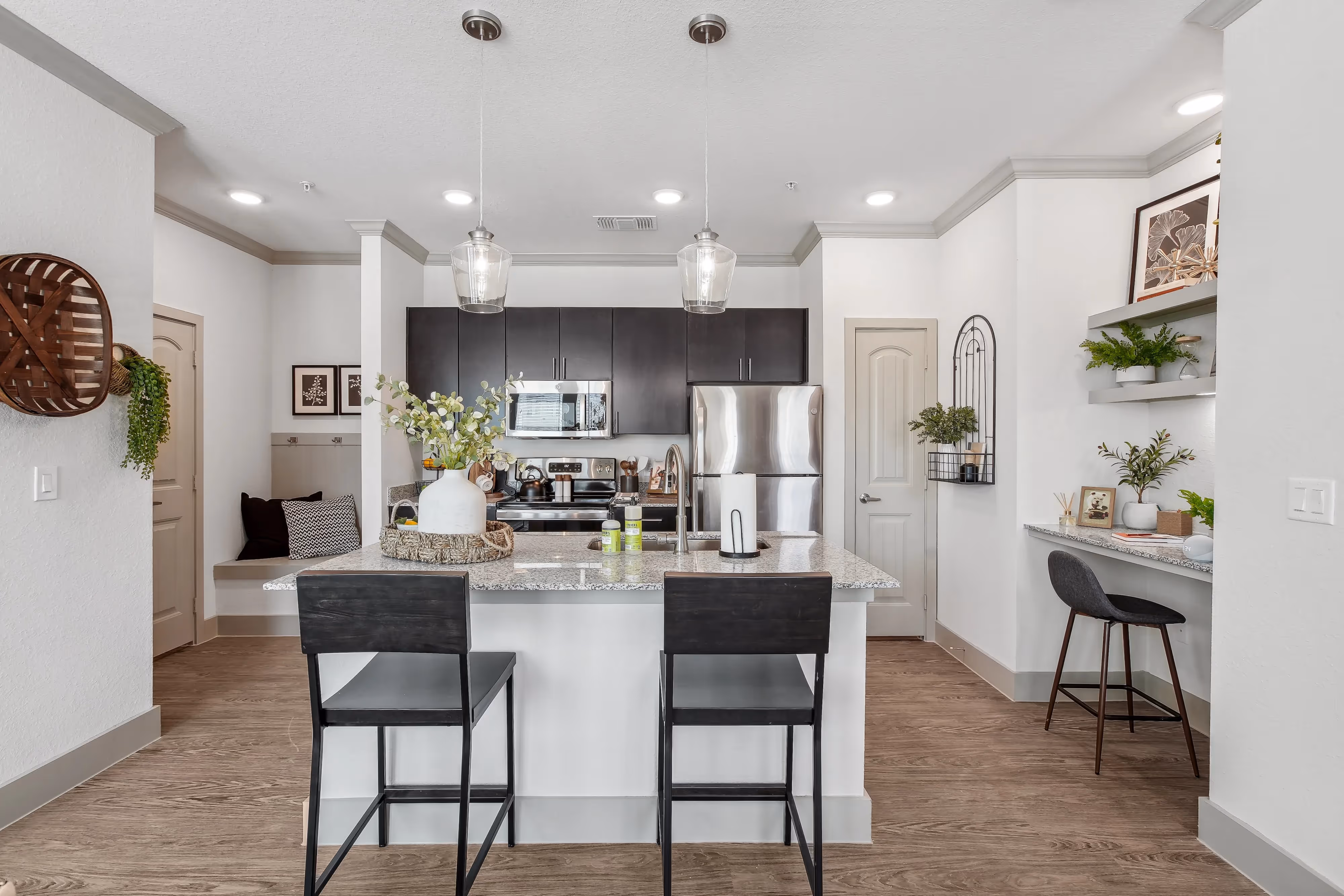 Kitchen with a granite-top island and dark wood cabinets, featuring a built-in bench seating area, at Paloma Luxury Apartments in San Antonio, TX.