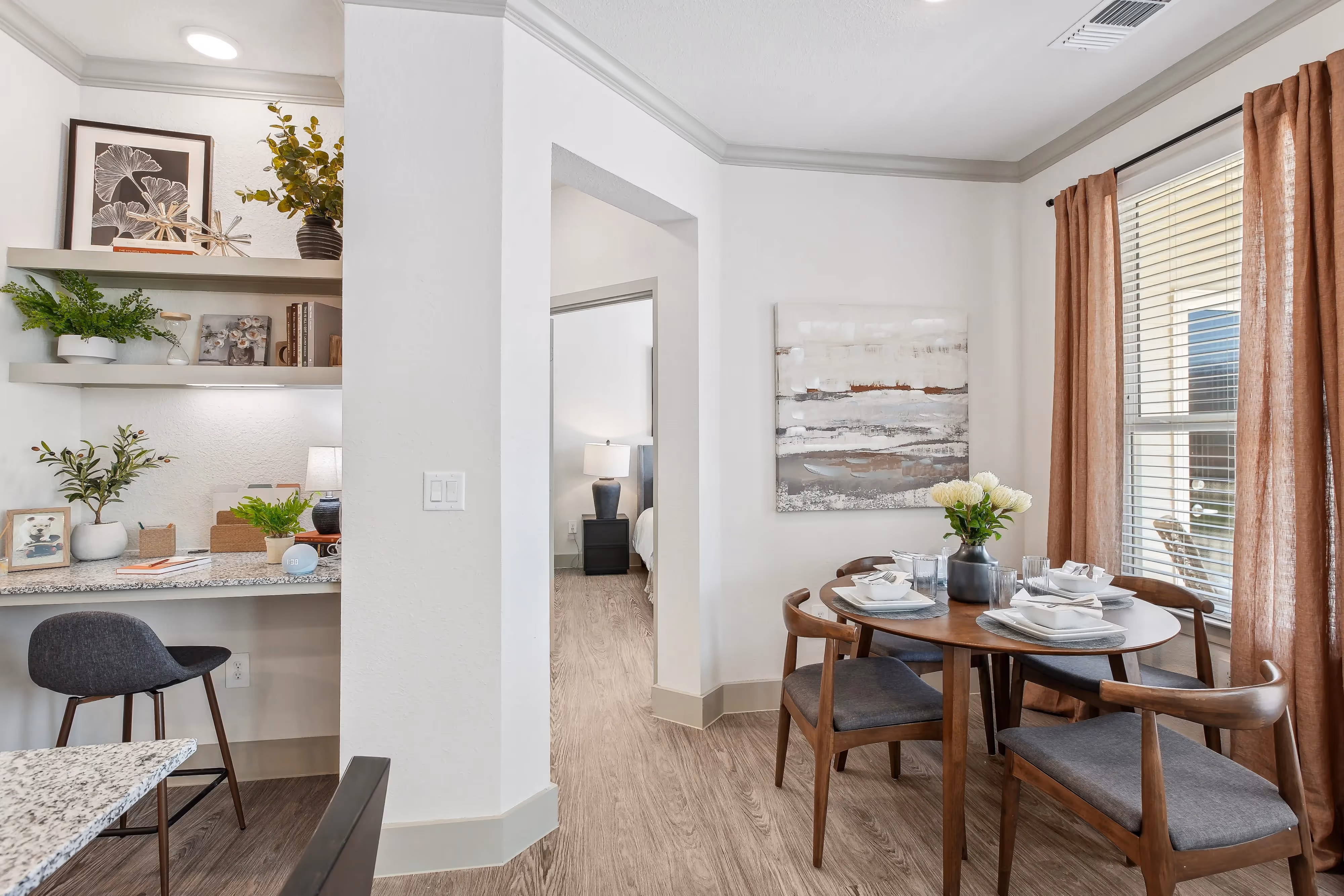 Apartment dining area with a round table and chairs, adjacent to a built-in desk or study nook, at Paloma Luxury Apartments in San Antonio, TX.