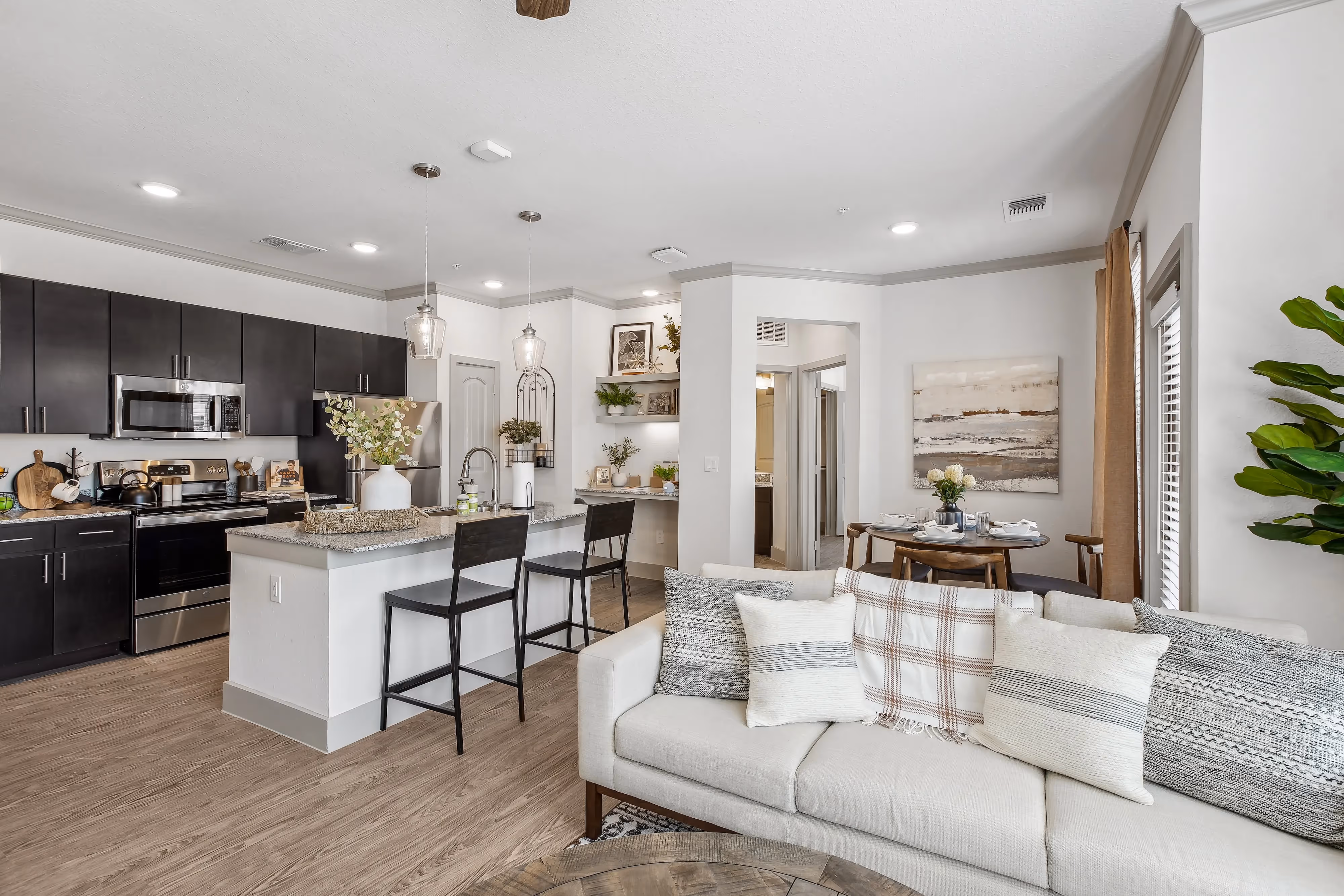 Open-concept apartment kitchen and living room with dark cabinetry and a dining area, at Paloma Luxury Apartments in San Antonio, TX.