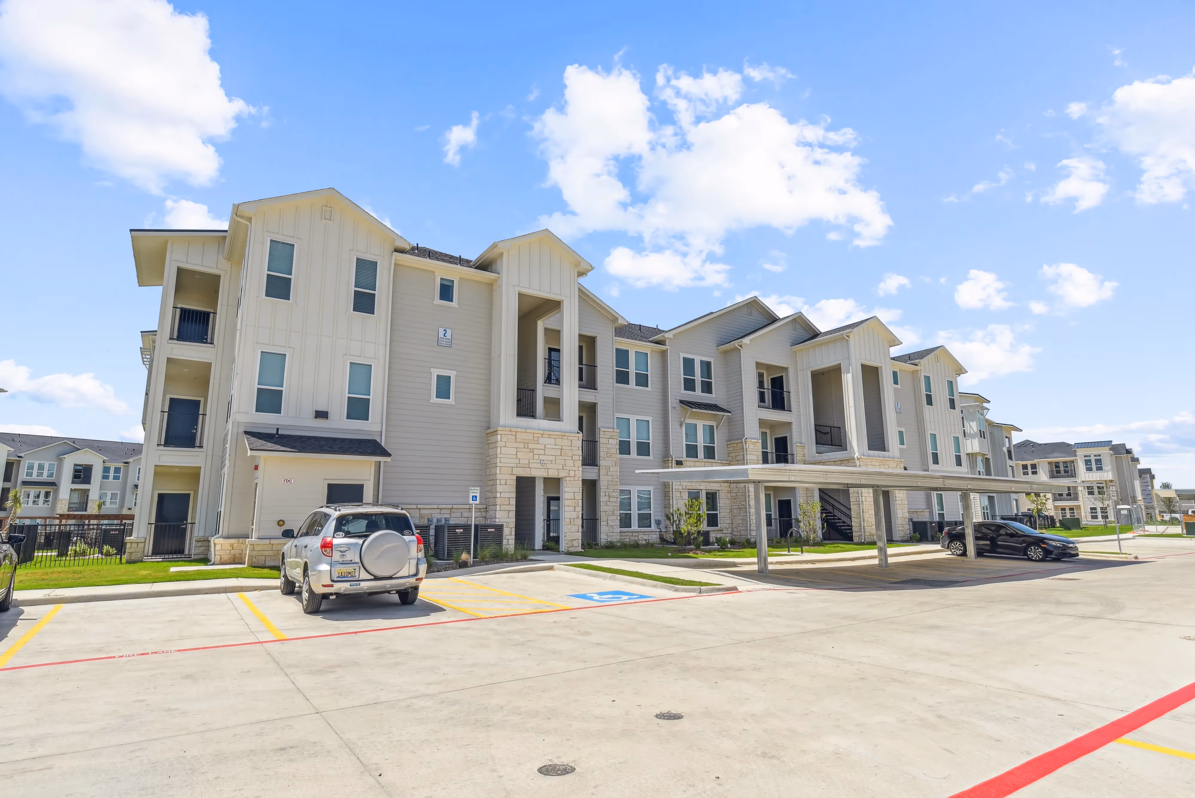 Exterior of a modern apartment building with covered parking and balconies, showcasing the architecture of Paloma Luxury Apartments in San Antonio, TX.