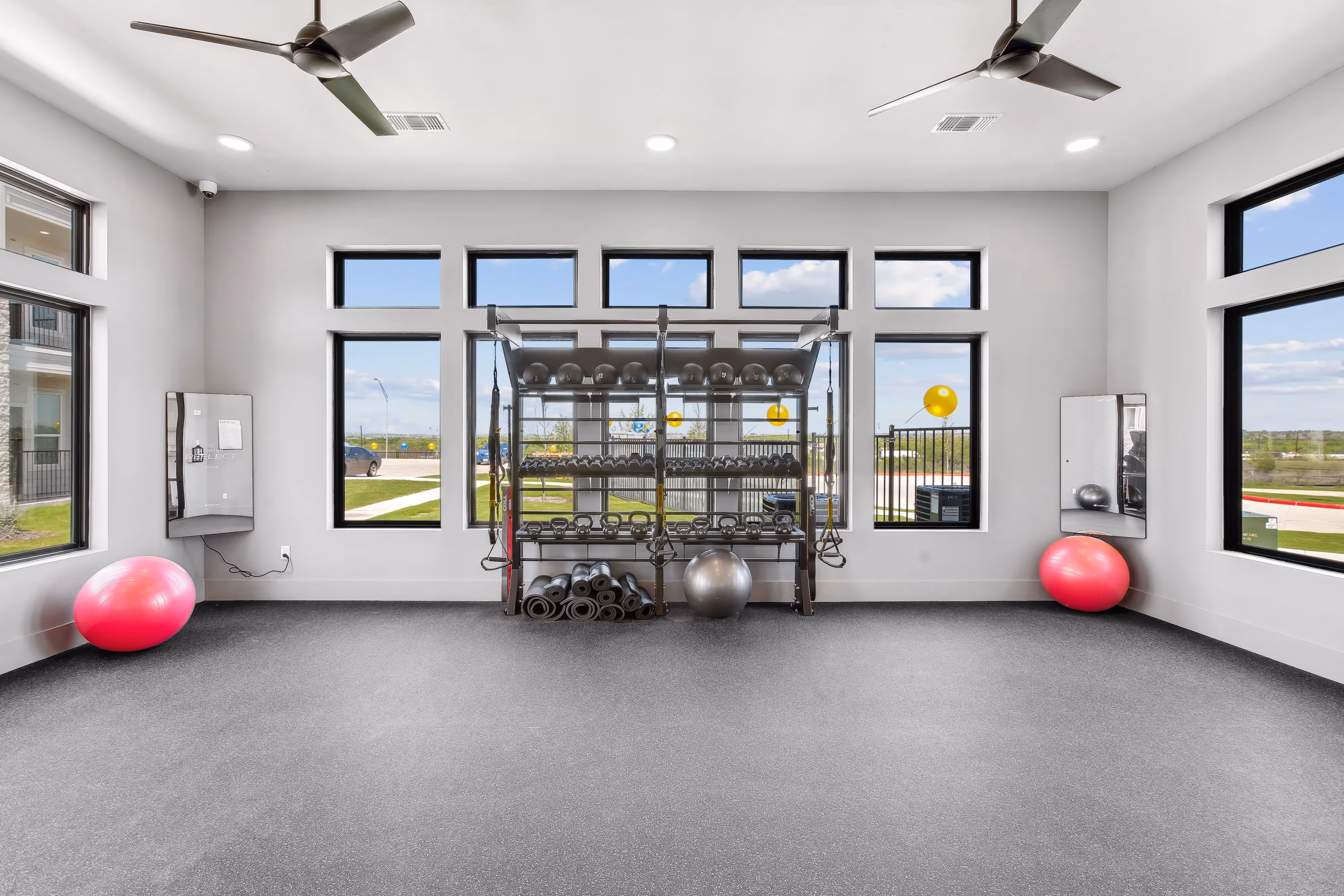 Resident fitness studio with a wide open floor space for yoga and stretching, and a wall of windows, at Paloma Luxury Apartments in San Antonio, TX.