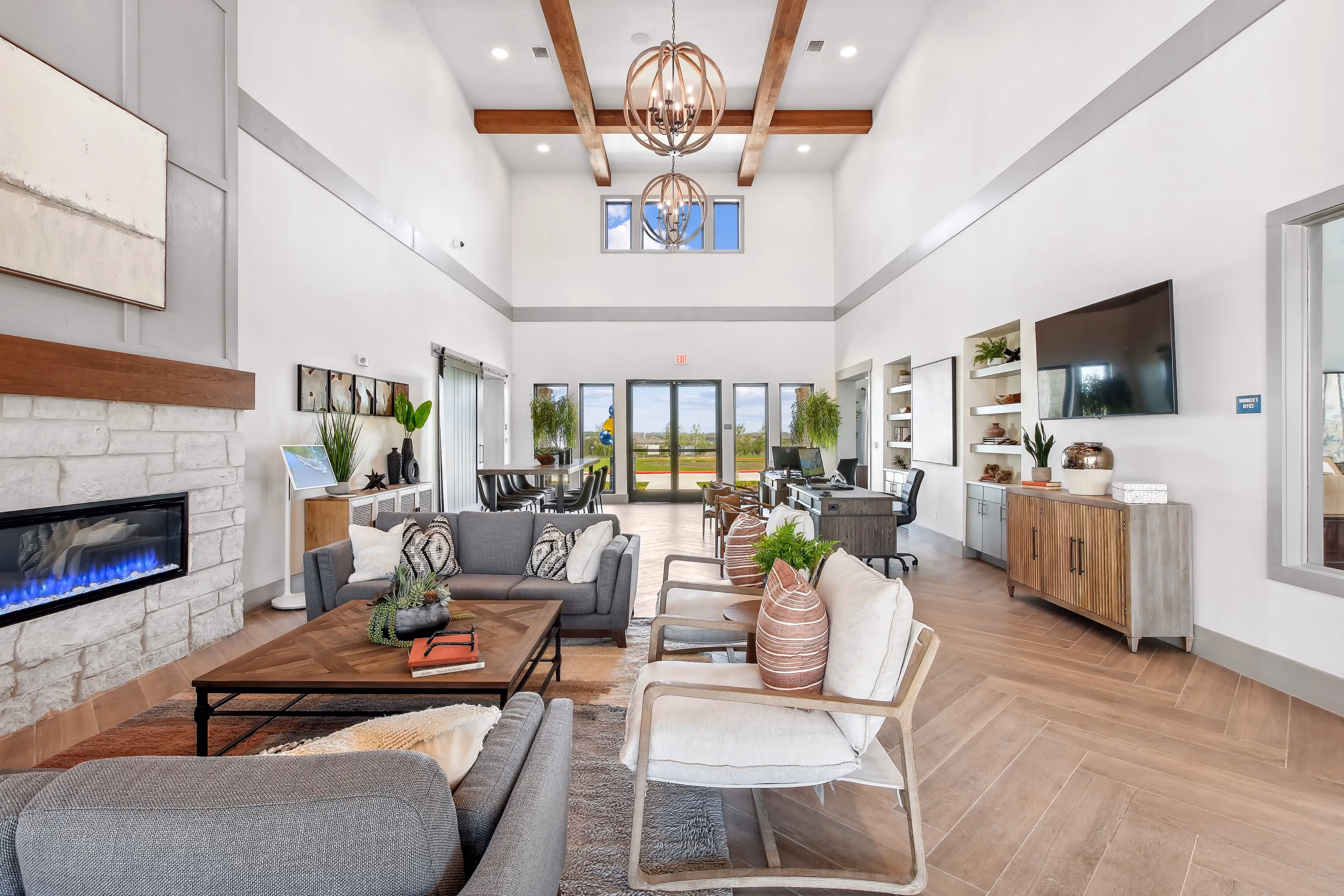Spacious and modern clubhouse lounge at Paloma in San Antonio, featuring cozy seating, a fireplace, and leasing office desks
