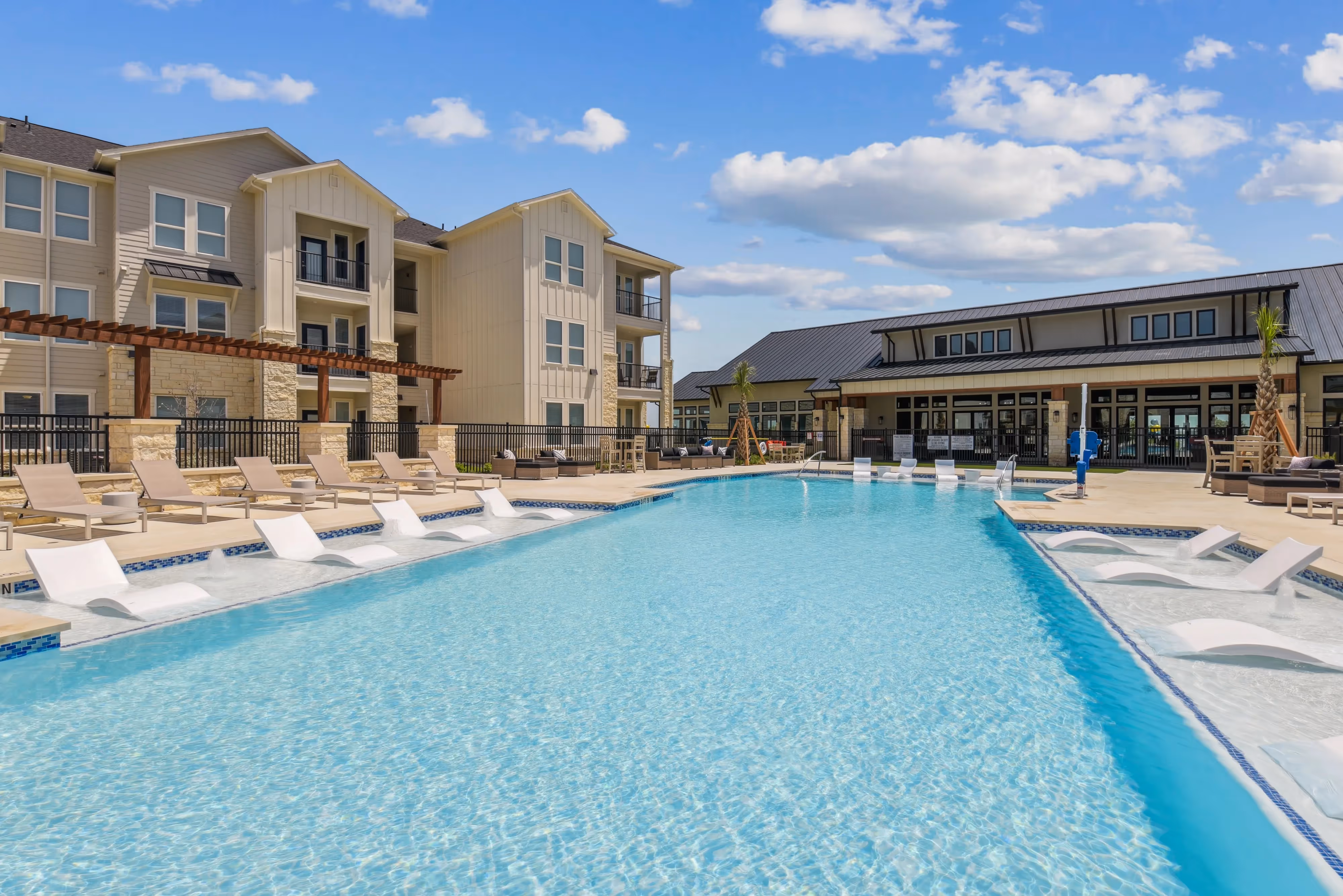 Resort-style swimming pool with in-pool loungers and a sundeck at Paloma Luxury Apartments in San Antonio, TX.