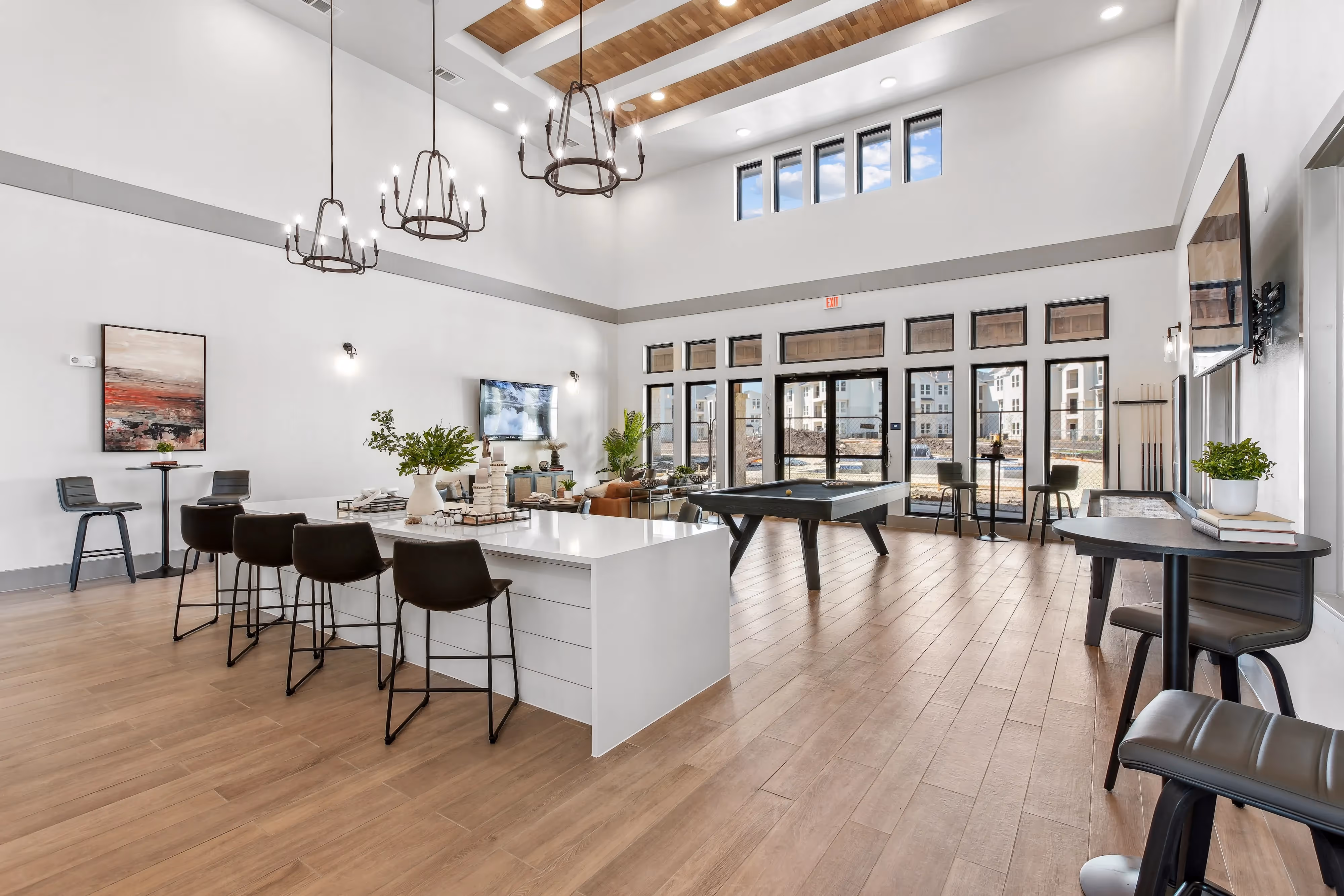 Spacious community clubhouse with high ceilings, large windows, a billiards table, and a bar area at Paloma Luxury Apartments in San Antonio, TX.