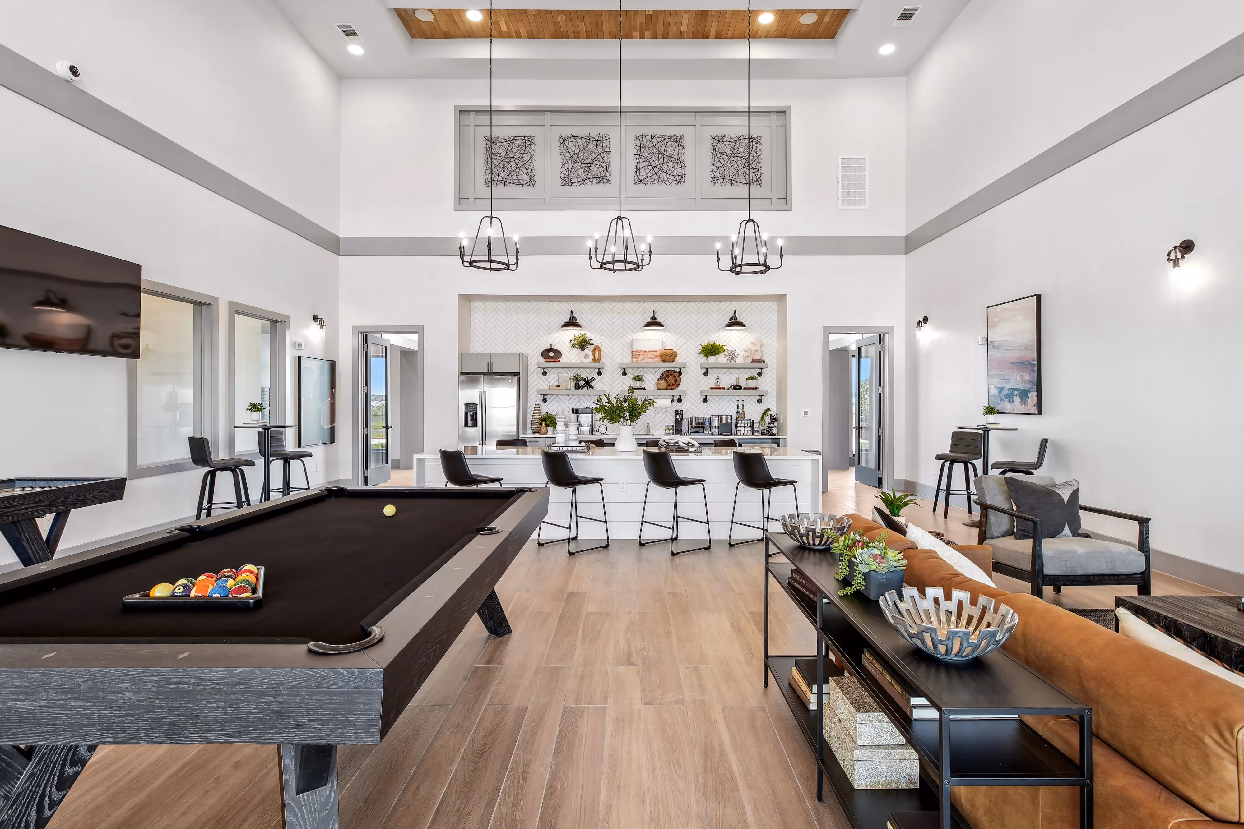 Bright and modern clubhouse with a kitchen island, billiards table, and comfortable seating, providing entertainment at Paloma Luxury Apartments in San Antonio, TX.