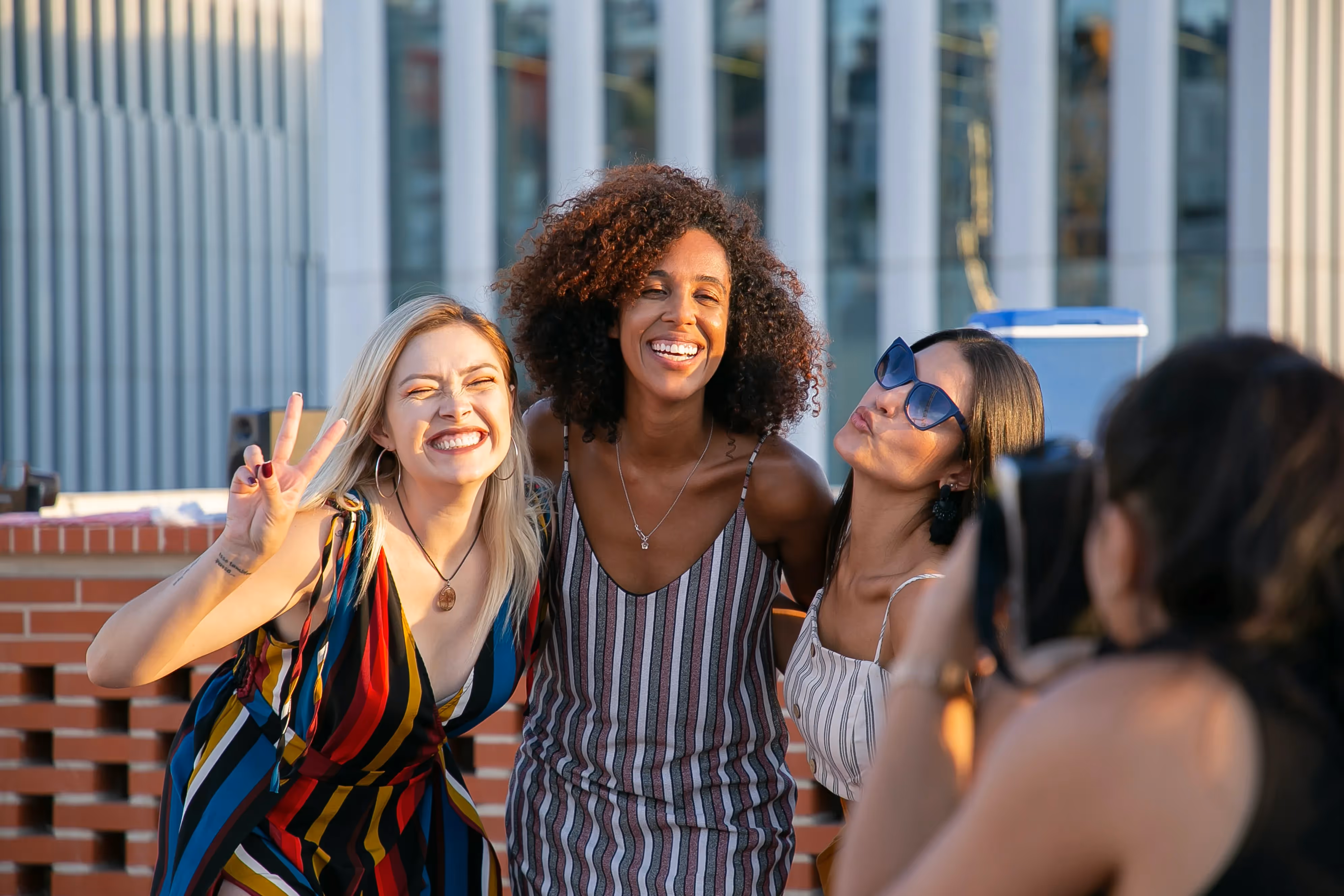A group of three women laughing and posing for a photo outdoors, representing the vibrant social life near Paloma Luxury Apartments in San Antonio, TX.