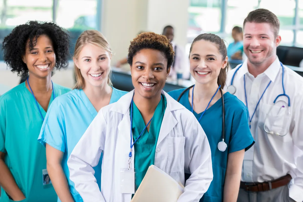 Group of healthcare professionals smiling in a hospital setting, representing Novumlogic healthcare technology solutions and HIPAA-compliant digital systems for medical organizations.