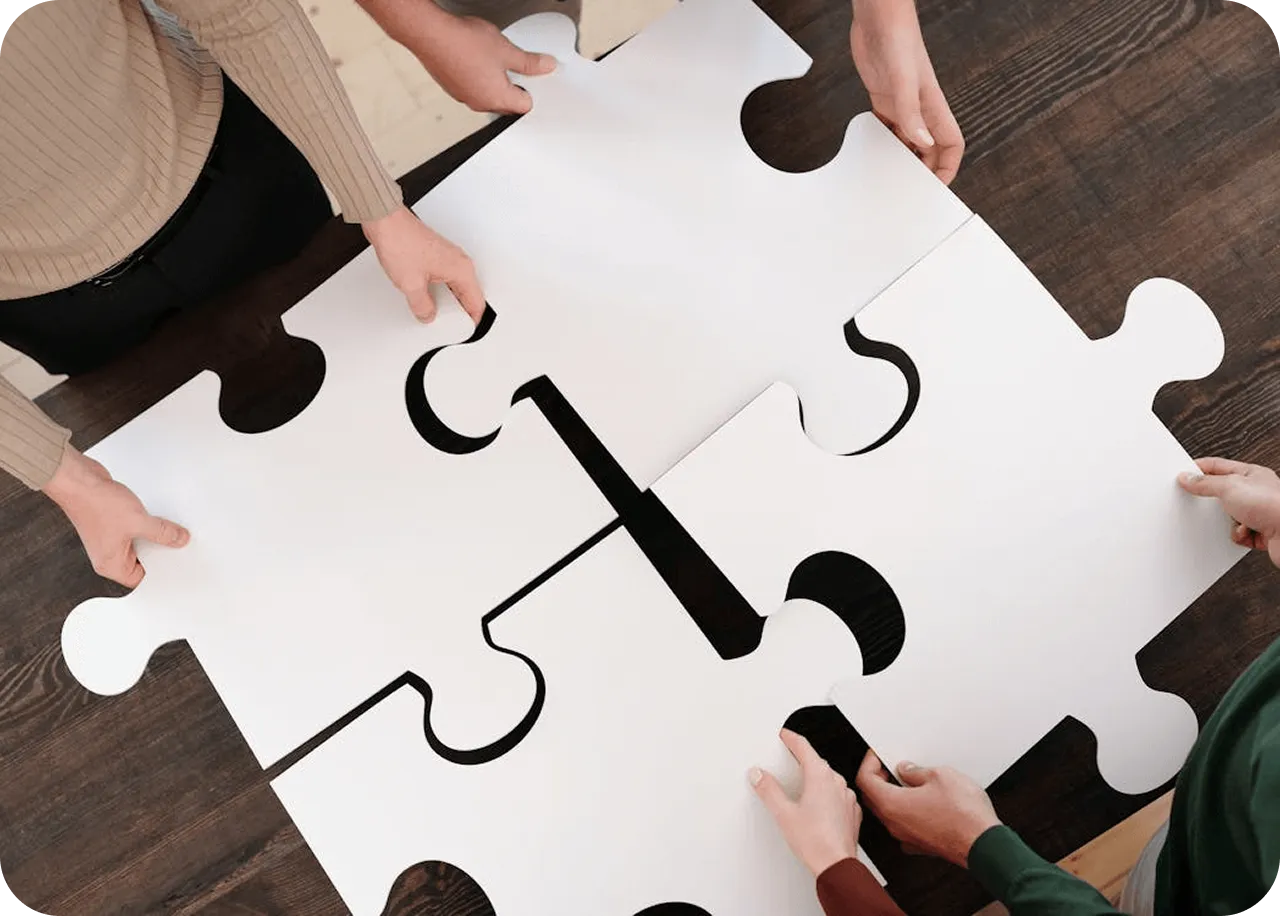 Team assembling puzzle pieces on a table representing collaboration and problem solving