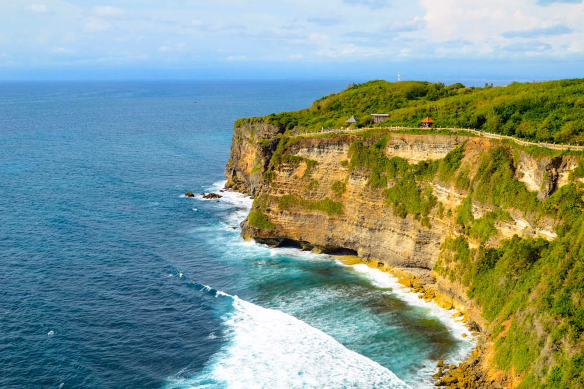 Uluwatu cliffs with green plants and waves below