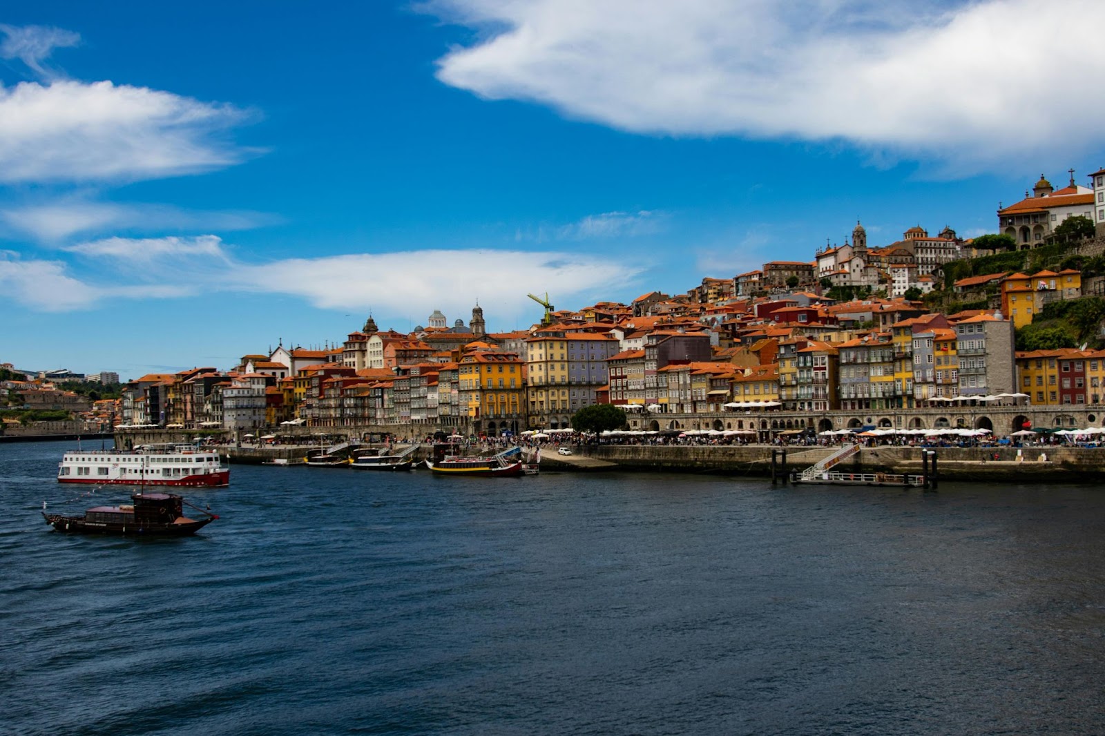 Colorful riverside buildings in Porto, with boats on the Douro River.