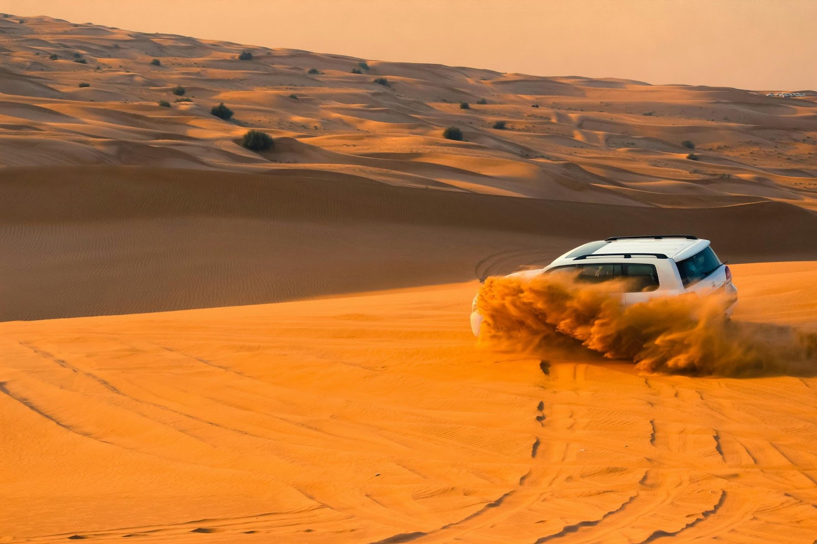 SUV speeding over golden sand dunes during a desert dune bashing adventure