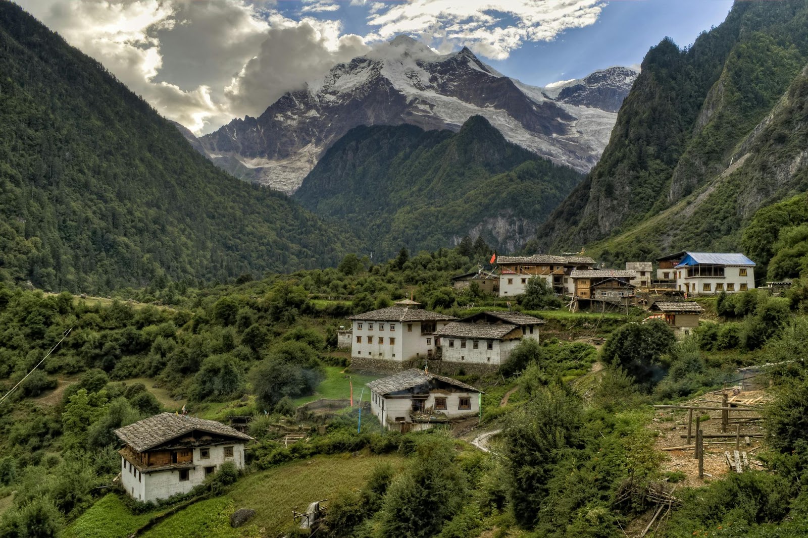 A traditional mountain village in Nepal with snow-capped peaks in the background.