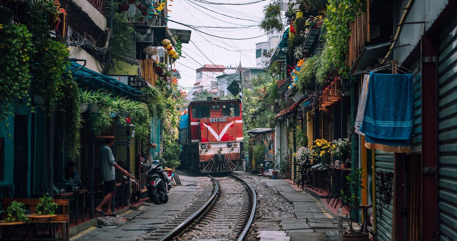 A red train passing through Hanoi’s famous Train Street, surrounded by narrow houses and cafes.