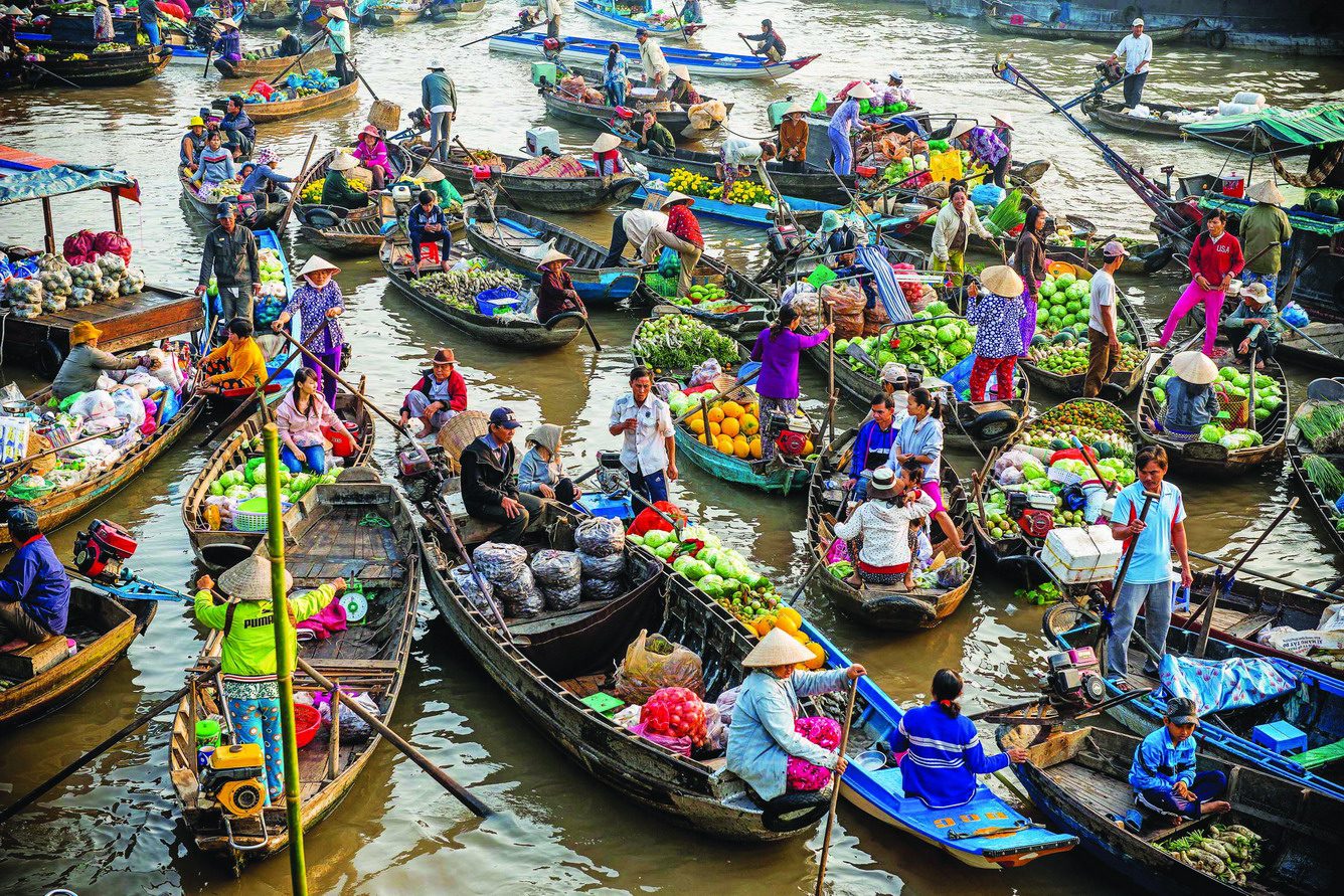 Crowded Cai Be Floating Market in Vietnam’s Mekong Delta, with colorful boats packed with produce and locals ‍
