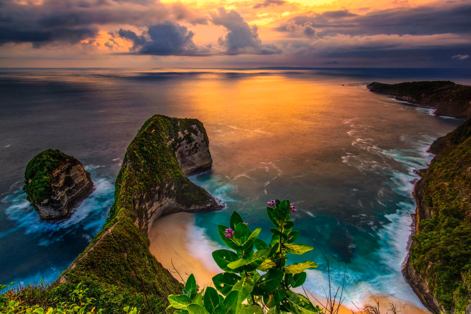 Keling king Beach in Bali at sunset, showing steep cliffs covered in green vegetation and a sandy cove.