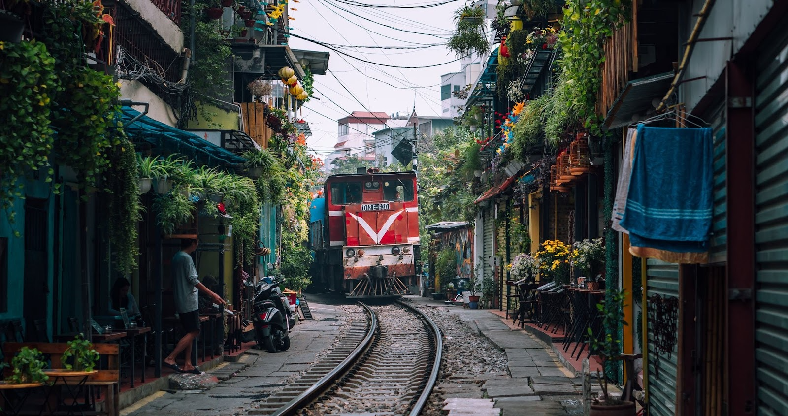 A red train passing through Hanoi’s famous Train Street, surrounded by narrow houses and cafes.