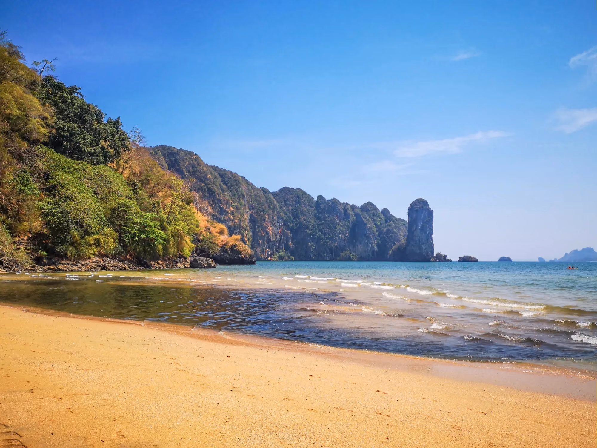 Boats floating on crystal-clear water at Phi Phi Islands in Thailand, with limestone cliffs.