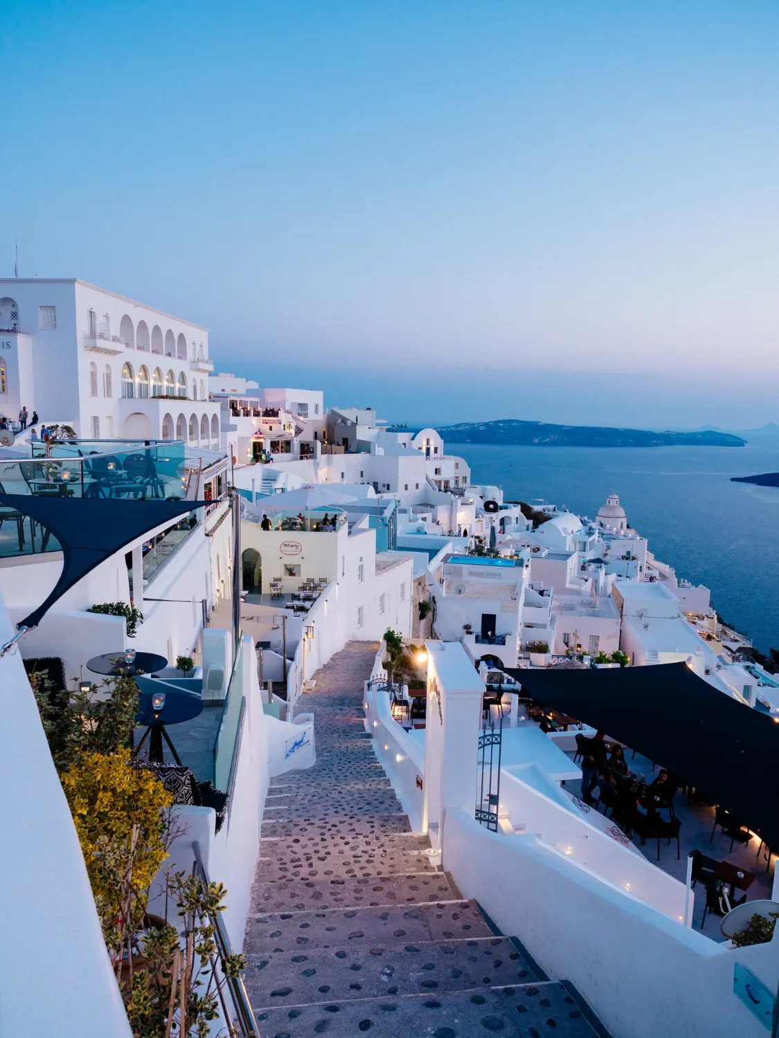 View of Santorini’s cliffside village featuring white buildings with blue domes overlooking the Aegean Sea.