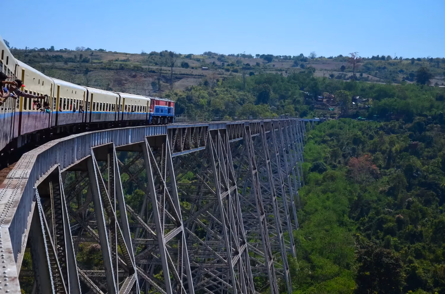  Train crossing the historic Nine Arches Bridge in Sri Lanka, surrounded with dense green forest and hills.