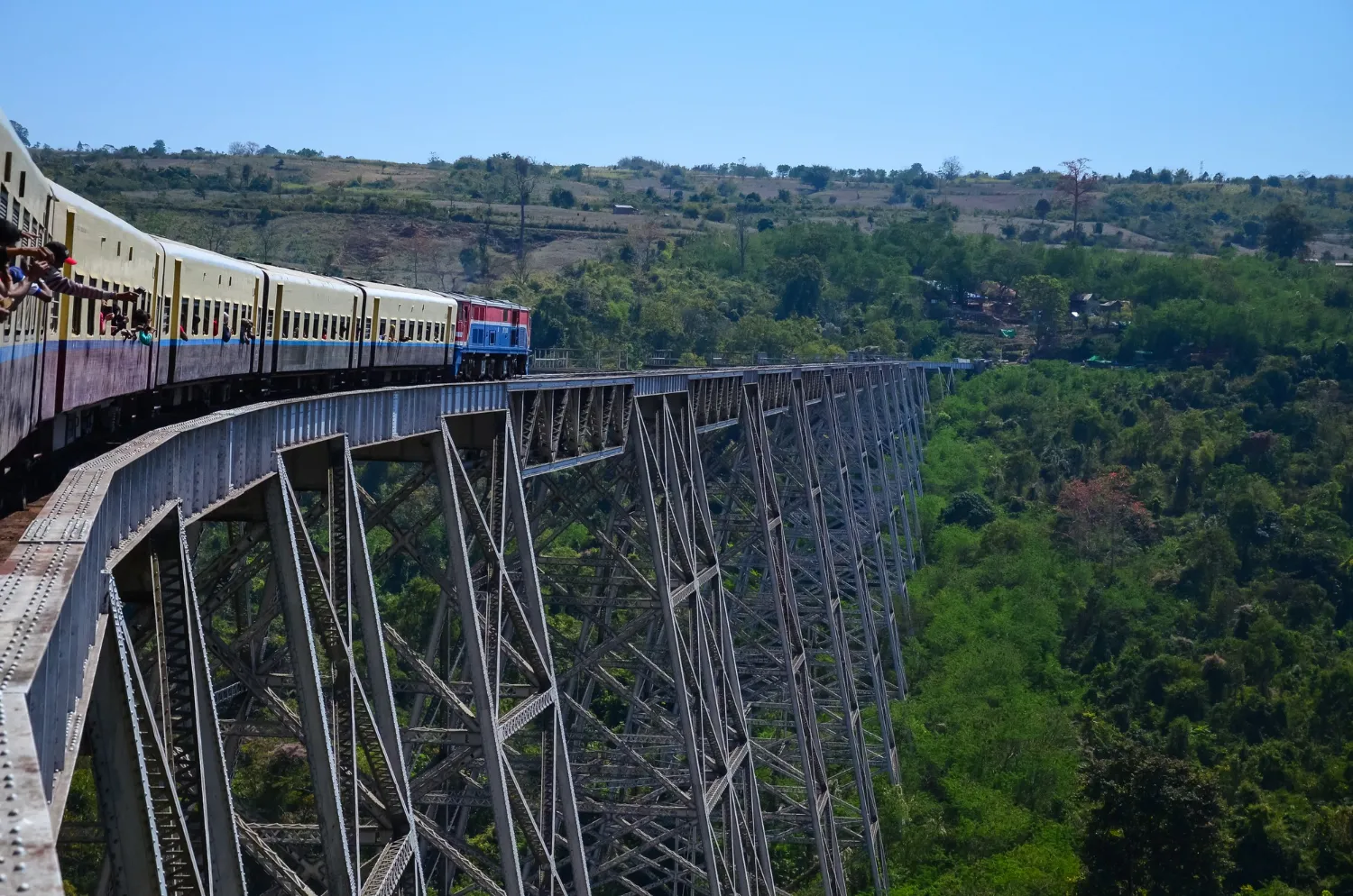  Train crossing the historic Nine Arches Bridge in Sri Lanka, surrounded with dense green forest and hills.