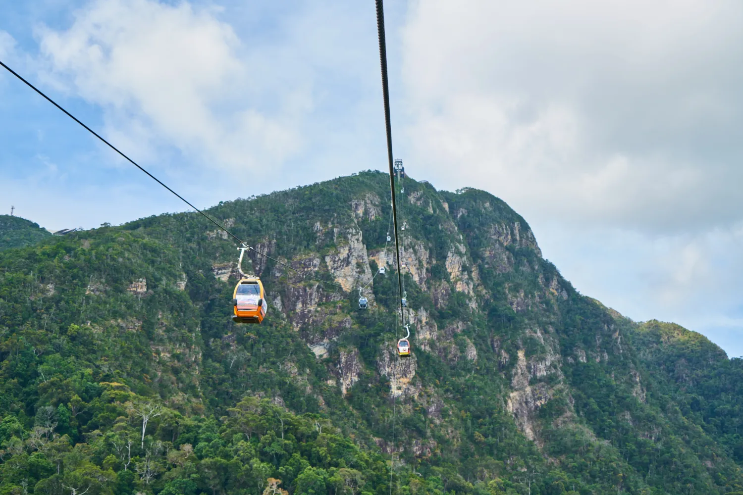 Langkawi SkyCab cable cars over tropical hills with breathtaking views of the blue sea and small islands in the Andaman Sea.