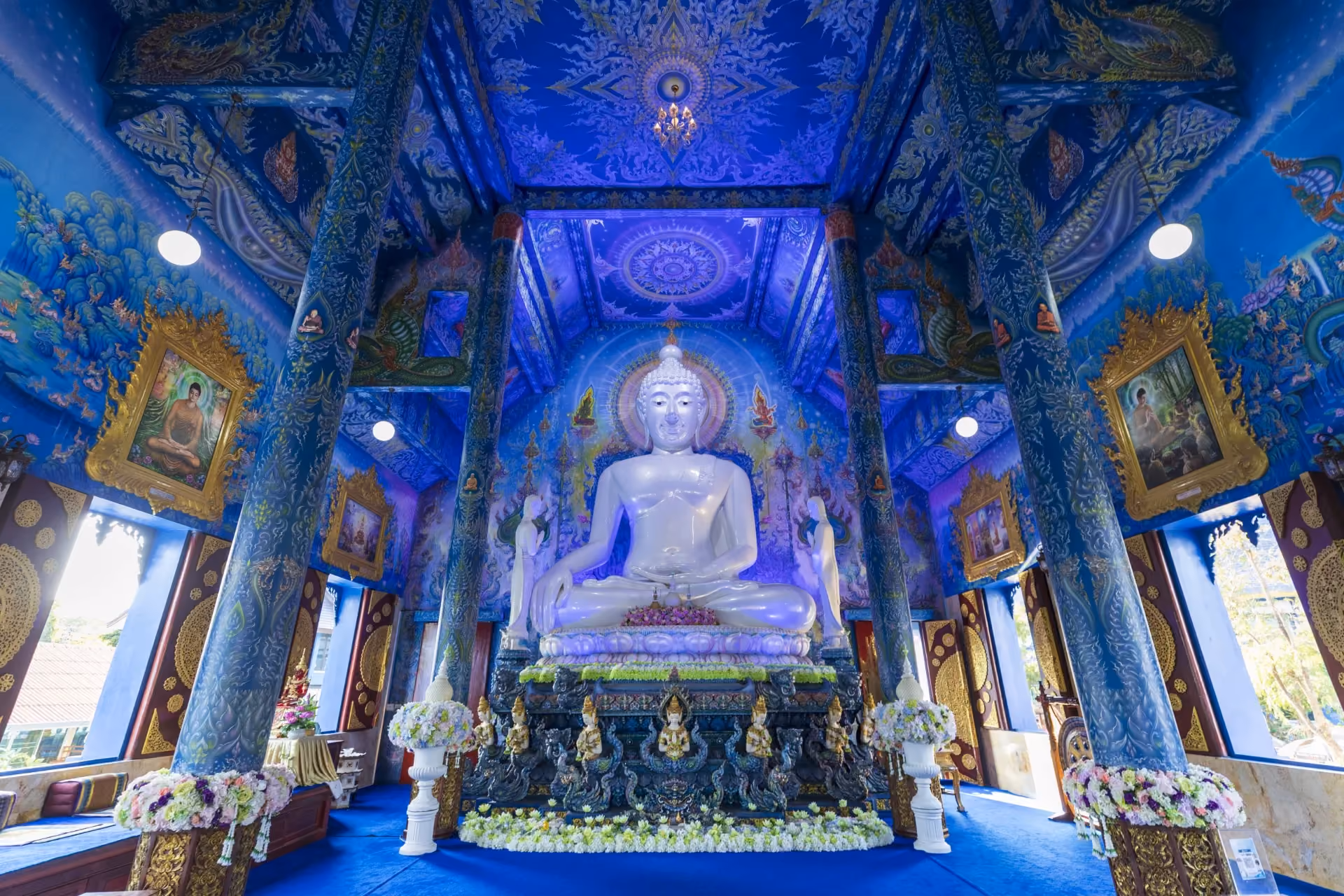 A vibrant blue temple with glowing murals and unique modern Buddhist art.