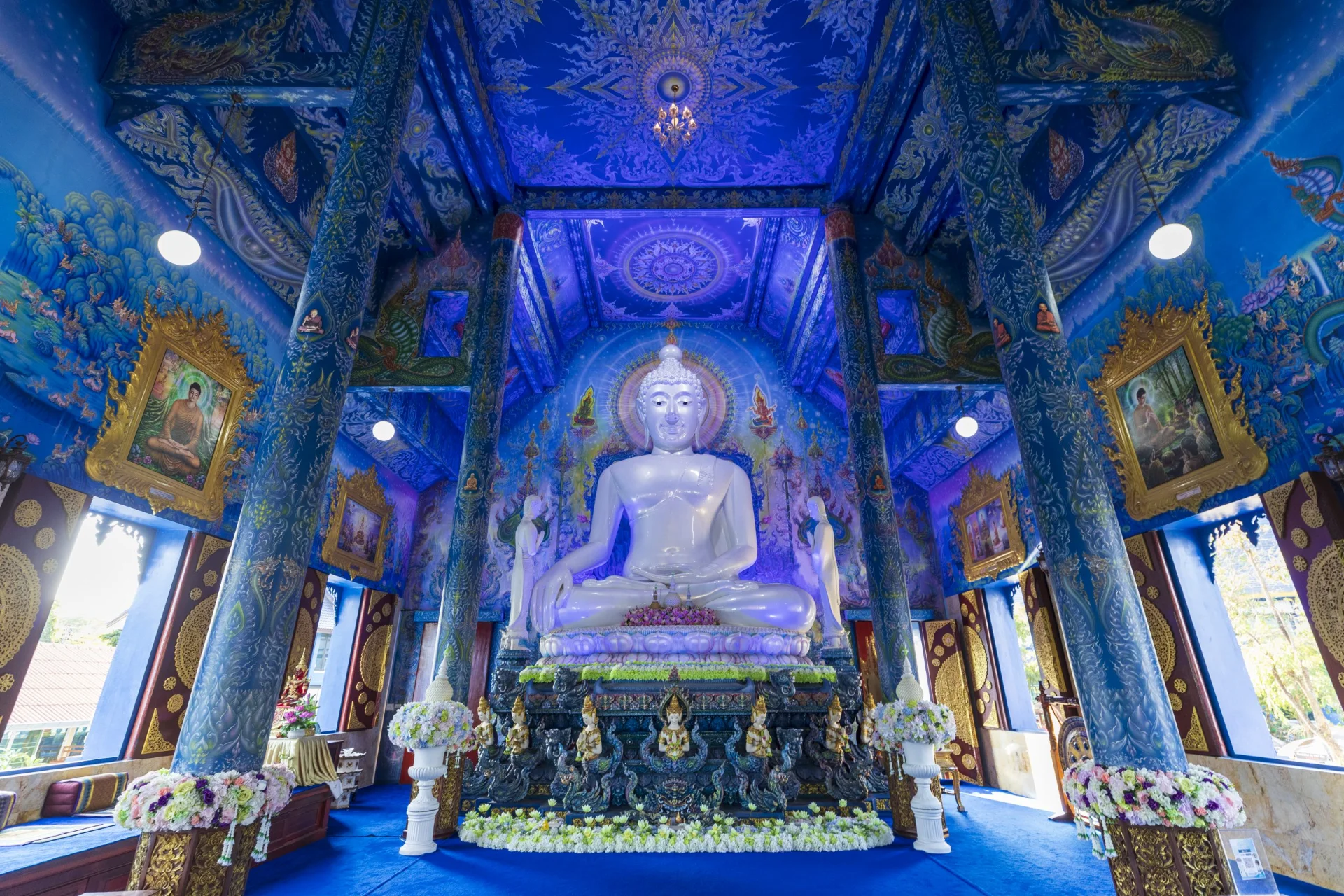 A vibrant blue temple with glowing murals and unique modern Buddhist art.