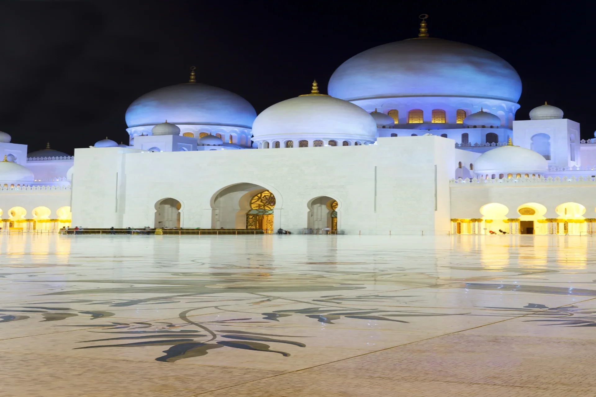 Sheikh Zayed Grand Mosque Abu Dhabi illuminated at night with white marble domes and golden arches, iconic UAE cultural heritage landmark for tourists