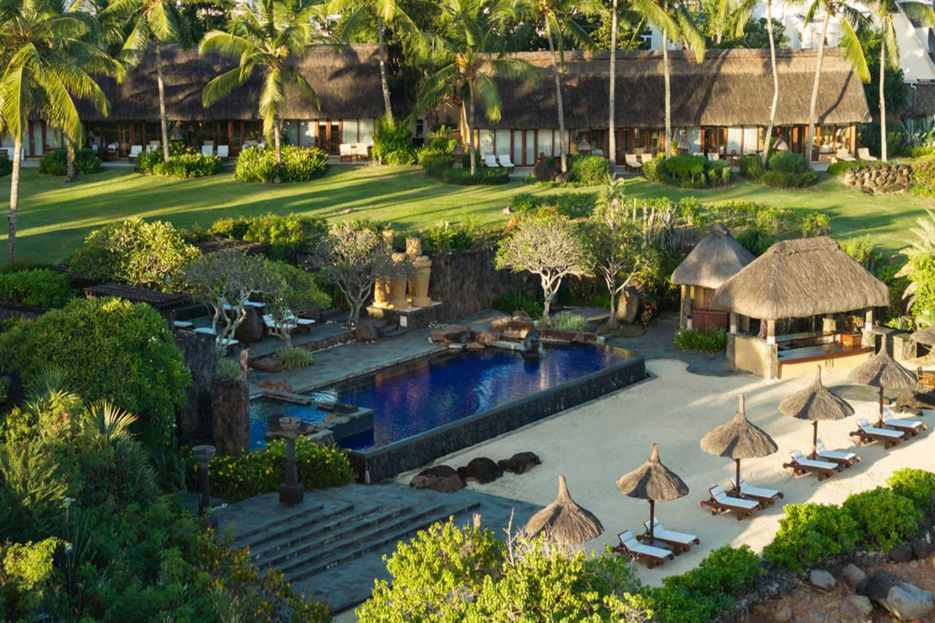 Aerial view of thatched luxury villas surrounded by lush gardens and pool, Oberoi Beach Resort Mauritius luxury stay- ultimate stay comaprison in maldives vs mauritius