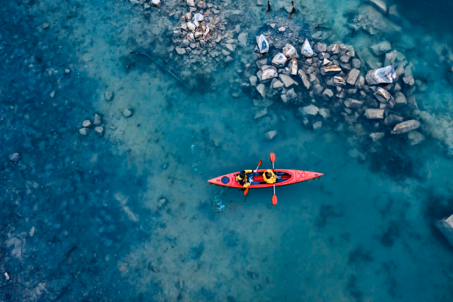 Aerial view of red kayak with two paddlers in turquoise water — adventure activity in Bali vs Thailand: The Ultimate Activity Comparison