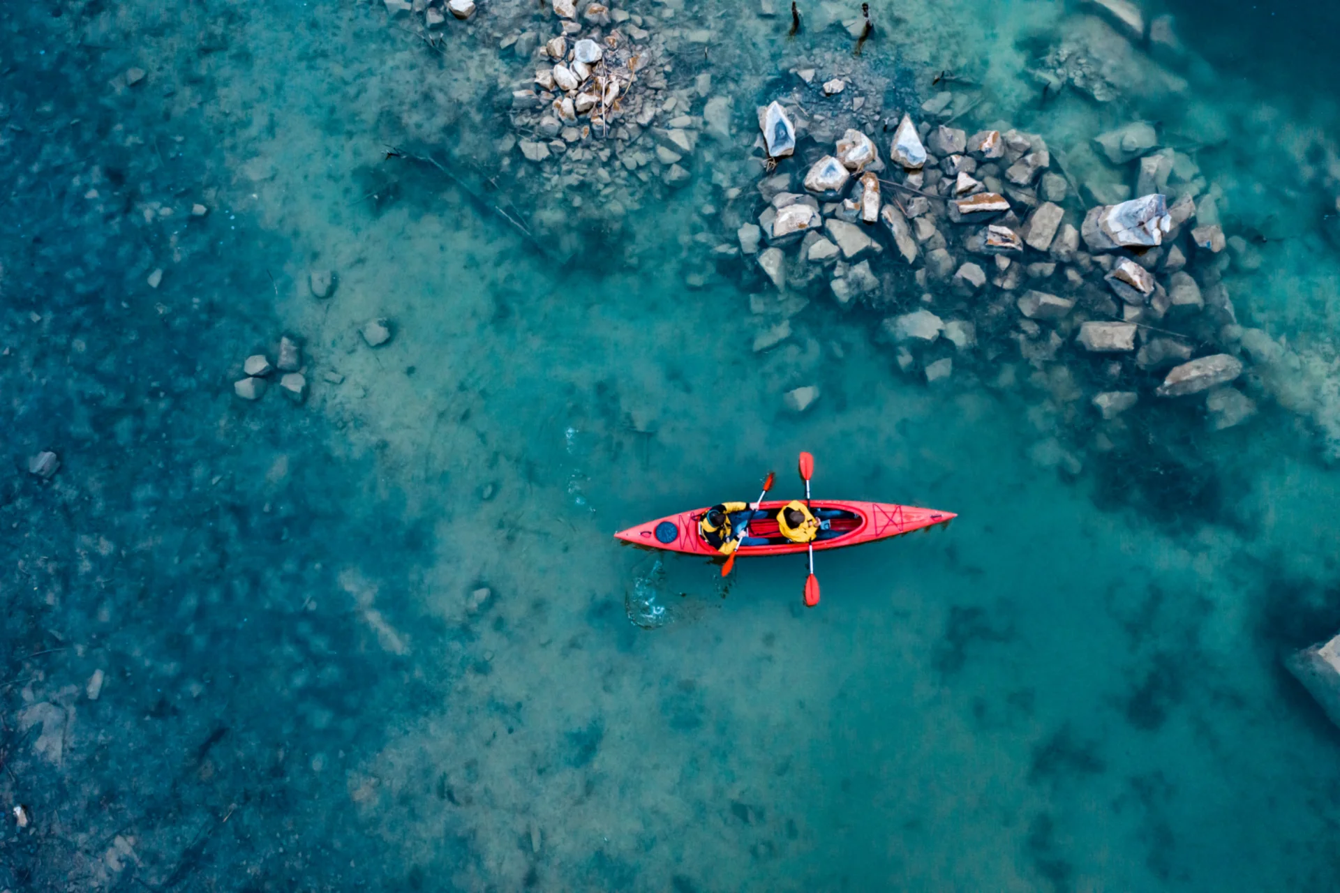 Aerial view of red kayak with two paddlers in turquoise water — adventure activity in Bali vs Thailand: The Ultimate Activity Comparison