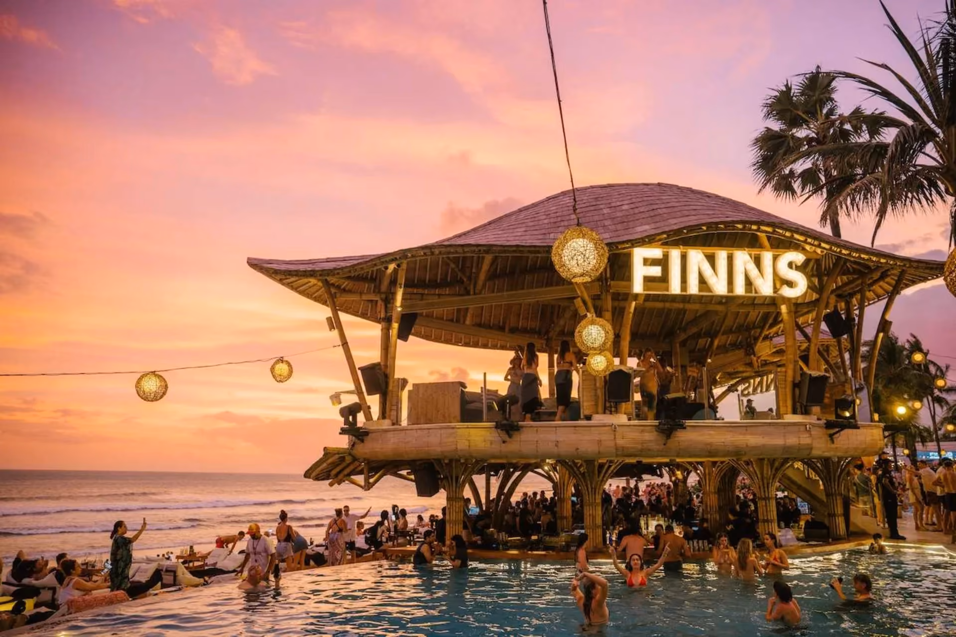 Finns Beach Club in Bali at sunset with crowd, pool, and bamboo stage — nightlife highlight in Bali vs Thailand: The Ultimate Activity Comparison