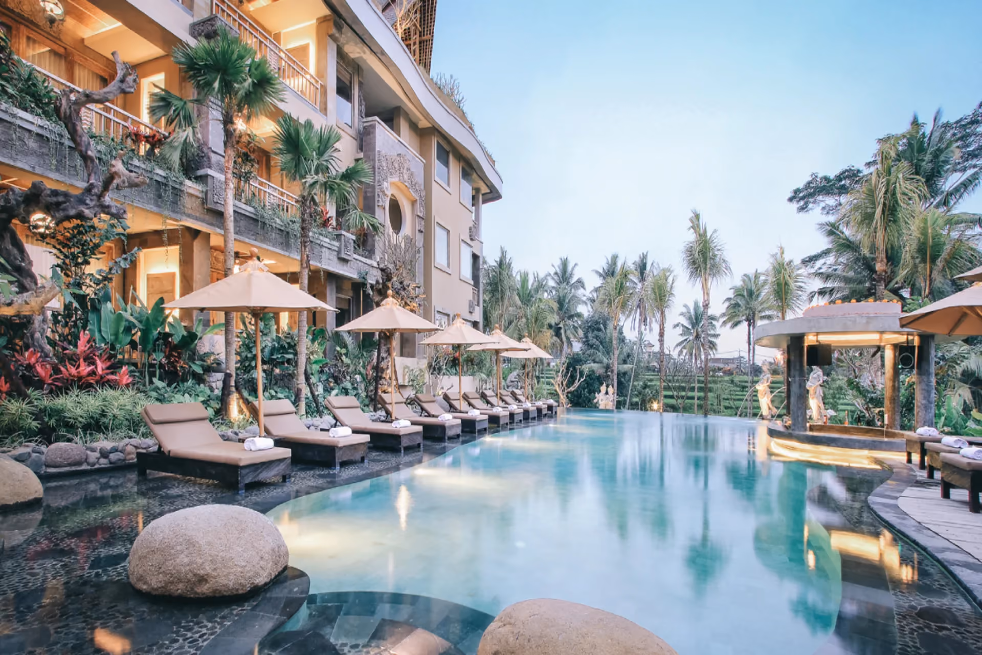 Kuwarasan – A Pramana Experience captures luxury Bali at its most immersive — a stunning infinity pool, ornate Balinese stonework, and lush rice terraces visible from every sun lounger.