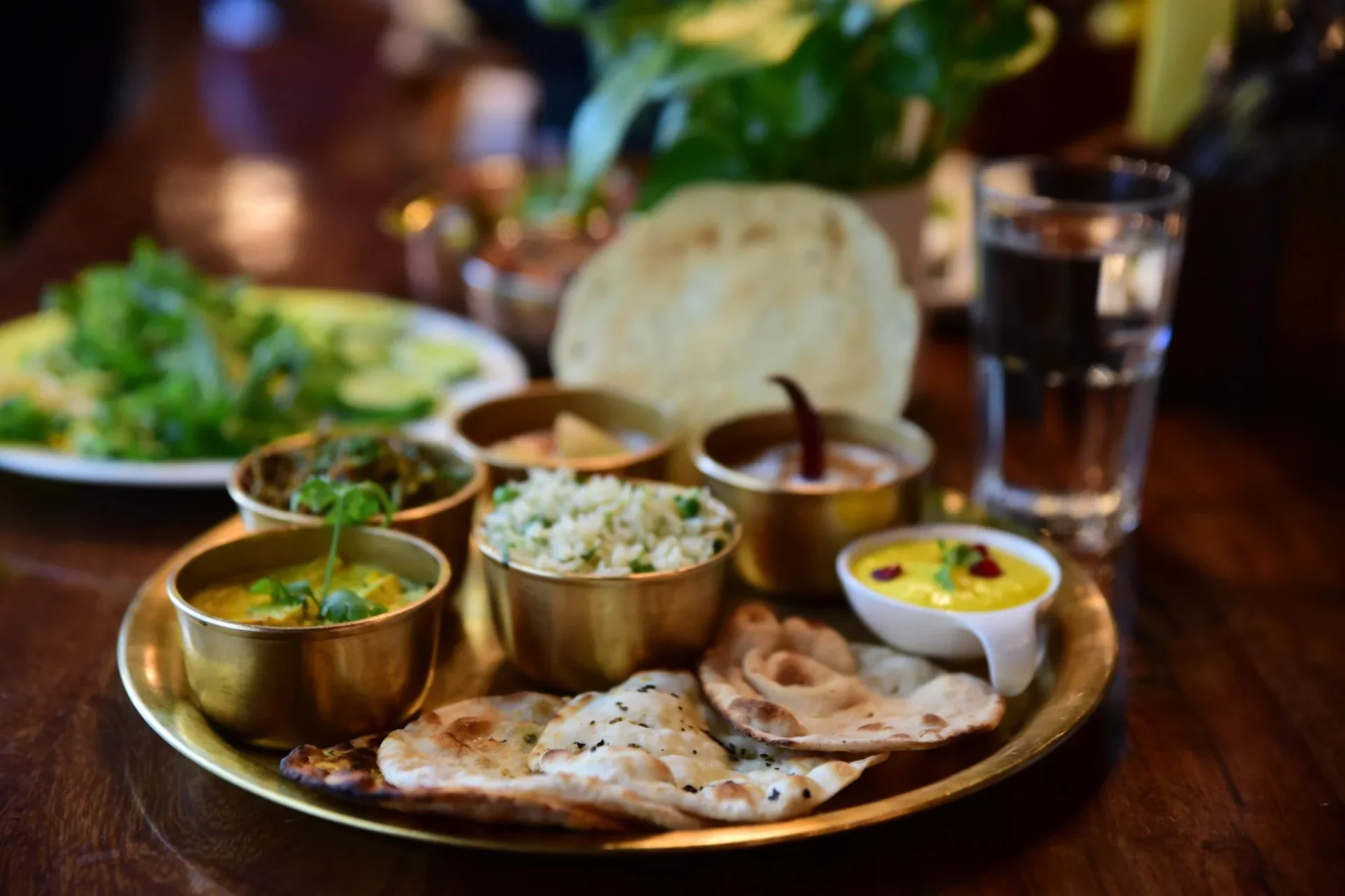 Price of Indian meals in Singapore and Dubai — a traditional Indian thali with dal, curry, rice, and naan served on a brass plate