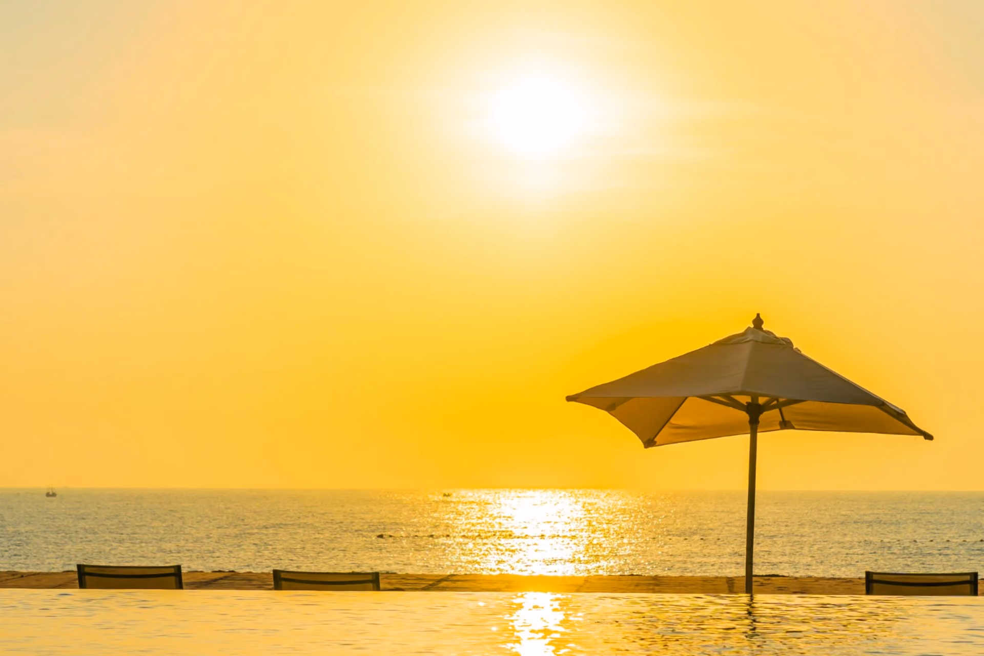 Beach umbrella at golden sunset by an infinity pool – Vietnam vs Thailand weather in July