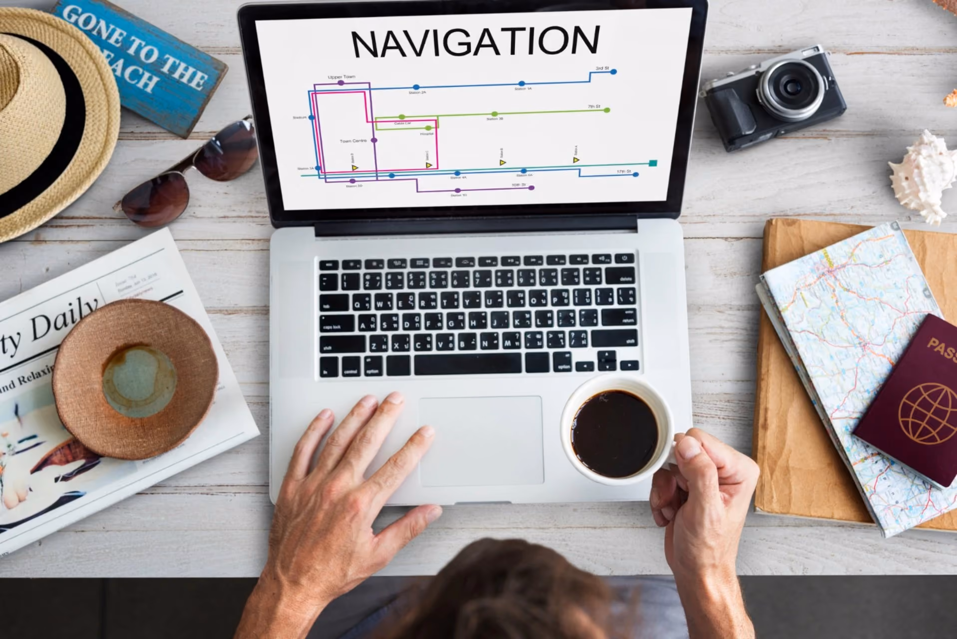 "Traveller planning navigation on laptop with passport and map — ease of navigation in New Zealand vs Switzerland