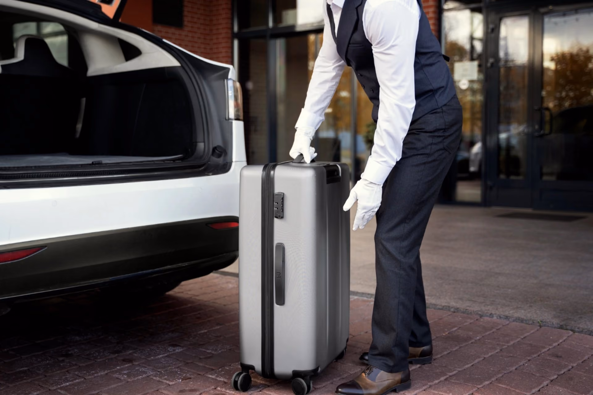 Hotel porter handling luggage from a car — transport simplicity in New Zealand vs Switzerland
